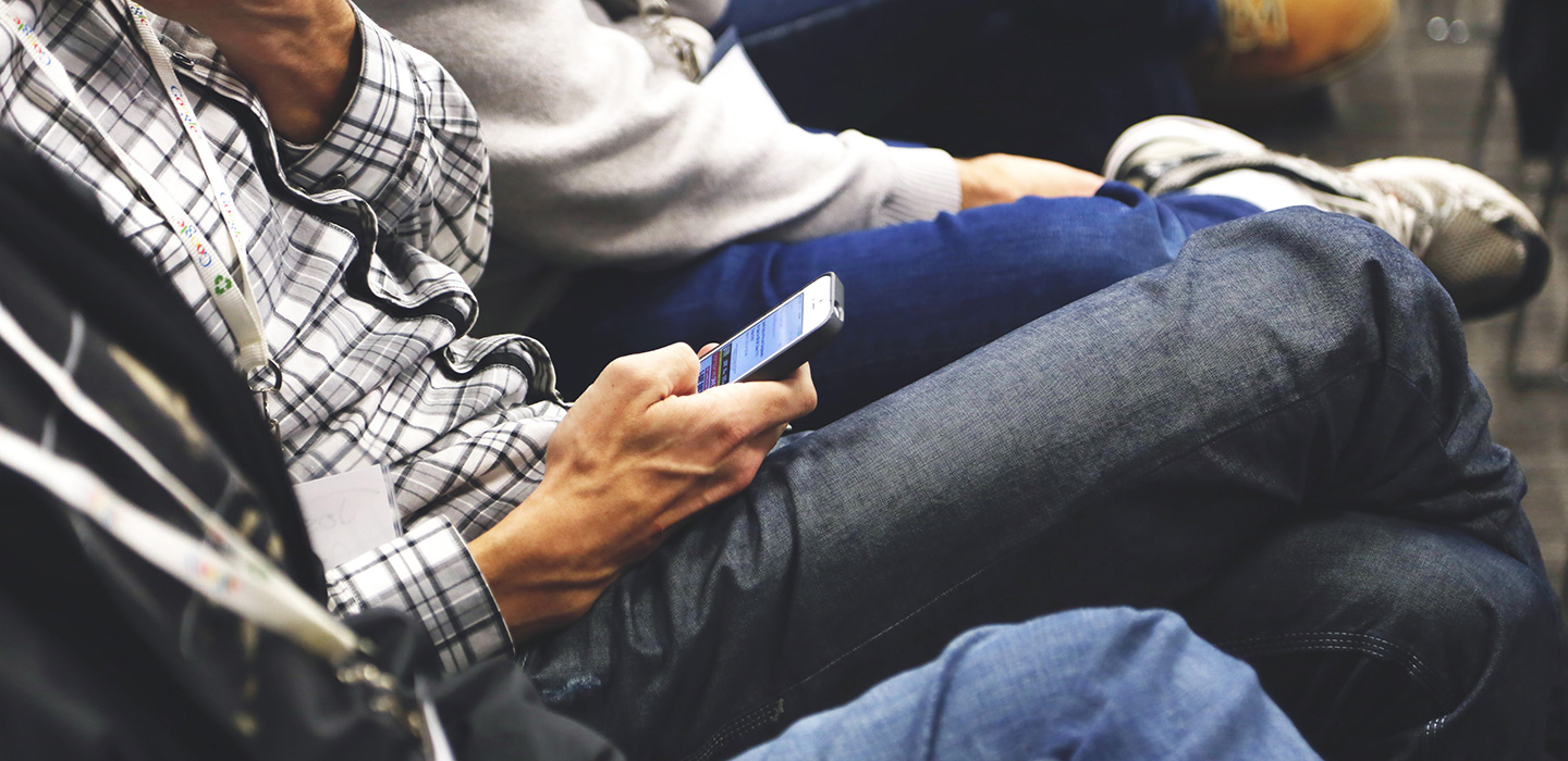 picture of a person listening at a conference and using an iPhone